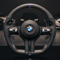 BMW steering wheel on display with cars in the background