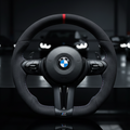 BMW steering wheel in a dark setting with blurred cars in the background